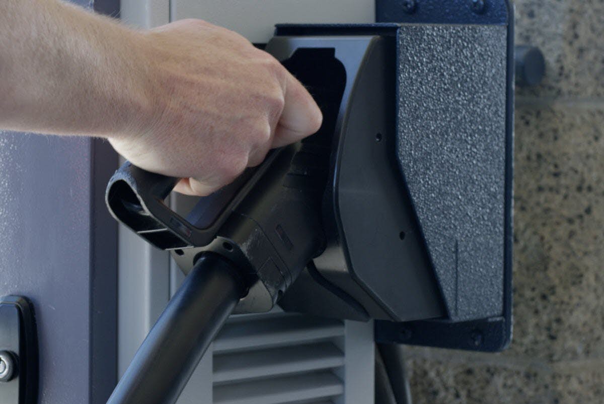 A hand holding a black pipe to a black object