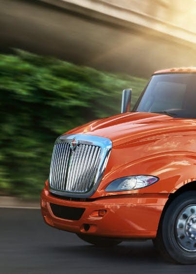 International truck driving on highway with city skyline in background