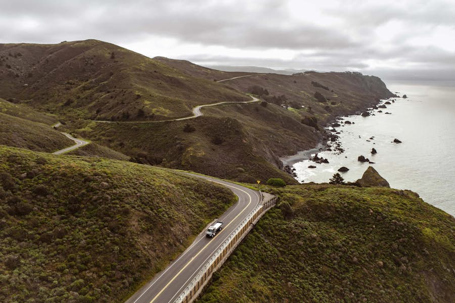 A road with a body of water and a car on the road