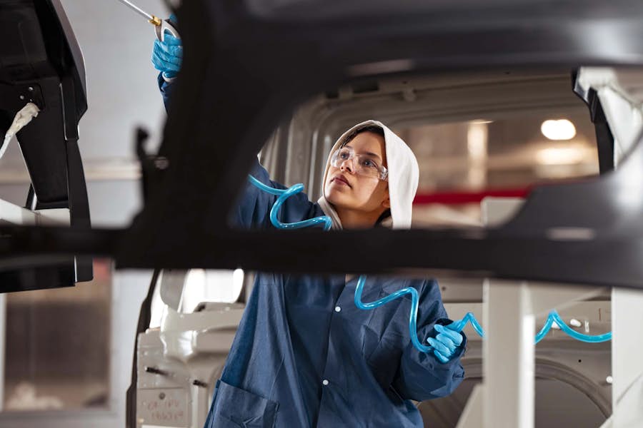 A person in a blue coat and goggles holding a blue hose