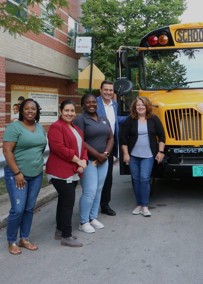 A group of people standing in front of a school bus
