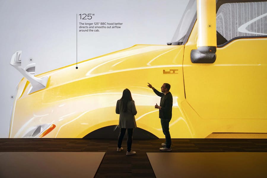 Two employees looking at image of yellow truck